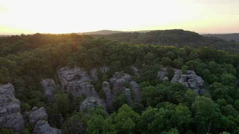 forest growing over rocky cliff with majestic sunrise, aerial view