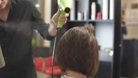 junge frau, die sich im salon die haare anziehen lässt