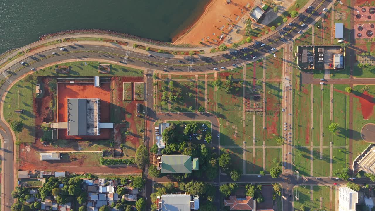 El Brete Bay in Posadas, Misiones, Argentina, featuring the sandy beach, curved avenue, green park, city grid, buildings, and shoreline along the Paraná River, drone shot, real time.