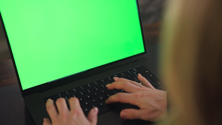 Frauenhand tippt auf einer Laptop-Tastatur mit Greenscreen. Nahaufnahme