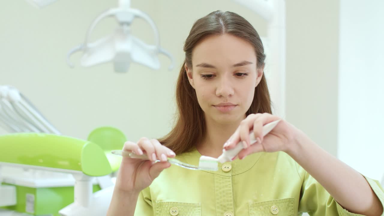 Beautiful girl squeezing toothpaste on toothbrush. Stomatology assistant