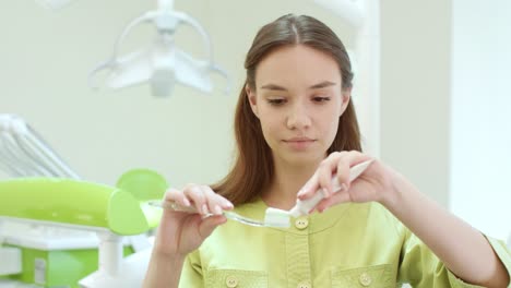 hermosa chica apretando pasta de dientes en el cepillo de dientes. asistente de stomatología
