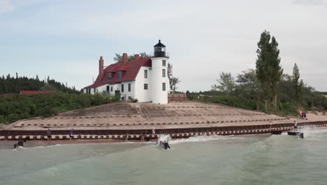 historic point betsie lighthouse in frankfort, michigan located along lake michigan with drone video low on water moving in