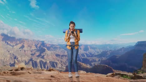 full body of asian female hiker with mountaineering backpack looking at the smartphone and saying wow while traveling at the top of mountain