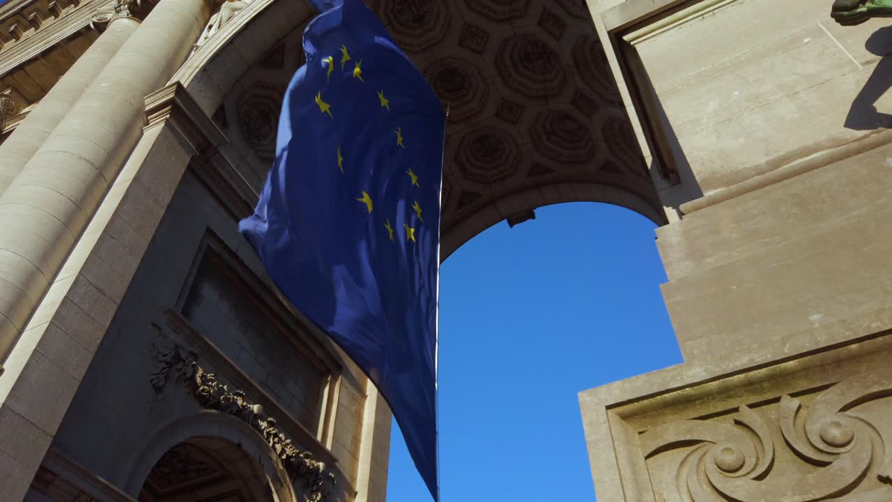 EU flag waving beneath historic arch in Brussels, Belgium
