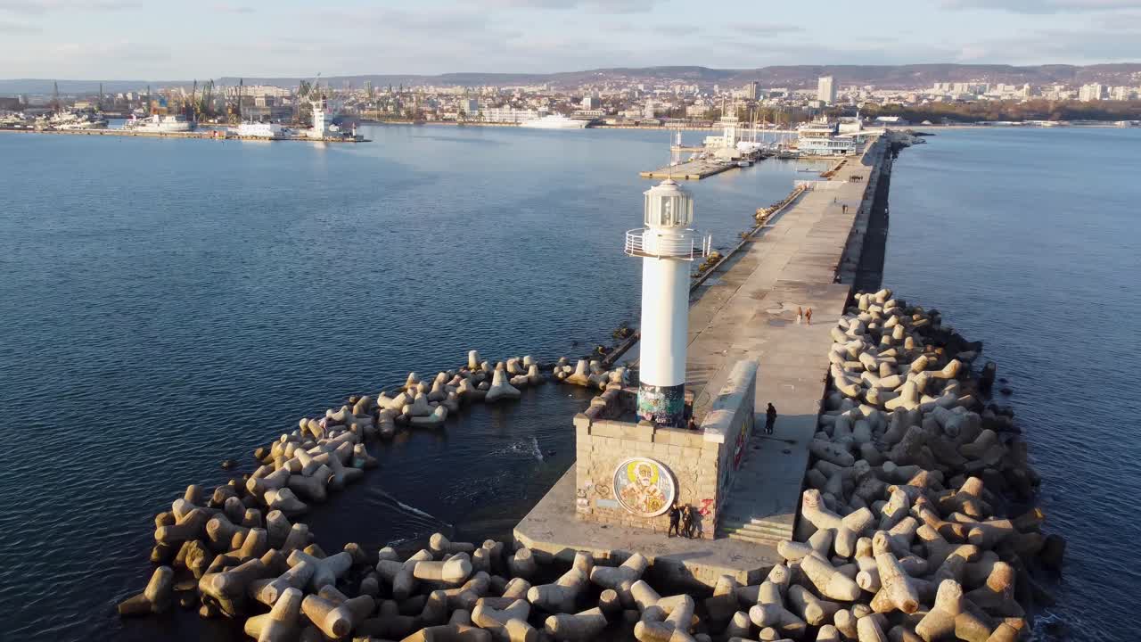 tiro de drone del faro en el muelle con el puerto de varna en la parte de atrás