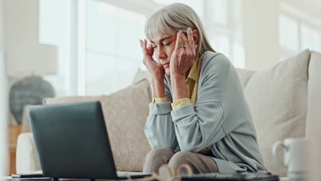 senior woman with headache in front of laptop