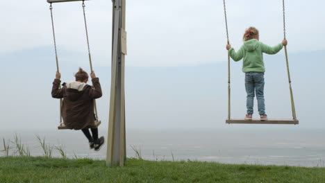 children swinging on the hill near the ocean