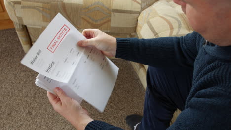 a man is opening a debt letter at home