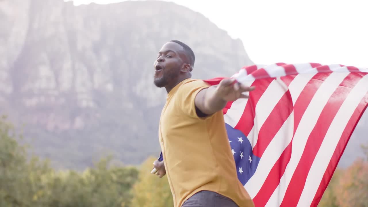 Retrato de hombre afroamericano sosteniendo la bandera de EE. UU. en el jardín, en cámara lenta