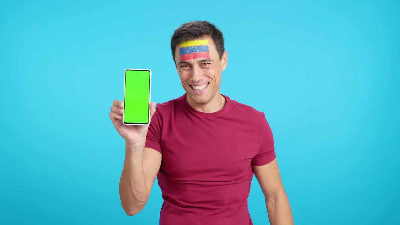 Venezuelan supporter looking at his mobile smiling and showing it