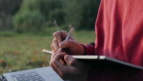 persona que escribe en un cuaderno al aire libre