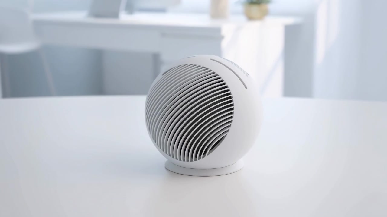 En högtalare står stilla i ett modernt inomhusutrymme med vita möbler och stora fönster, sedd från en sidovinkel, vilket skapar en neutral och professionell atmosfär med inslag av plast och metall.