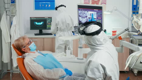 stomatologist in coverall and patient looking at digital dental x-ray