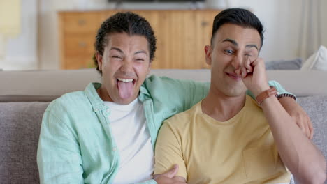 happy diverse gay male couple having video call and making funny faces at home, slow motion