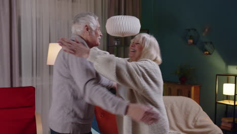 Happy-senior-people-couple-dancing-at-home-relaxing-having-fun-with-modern-music-smiling-at-home