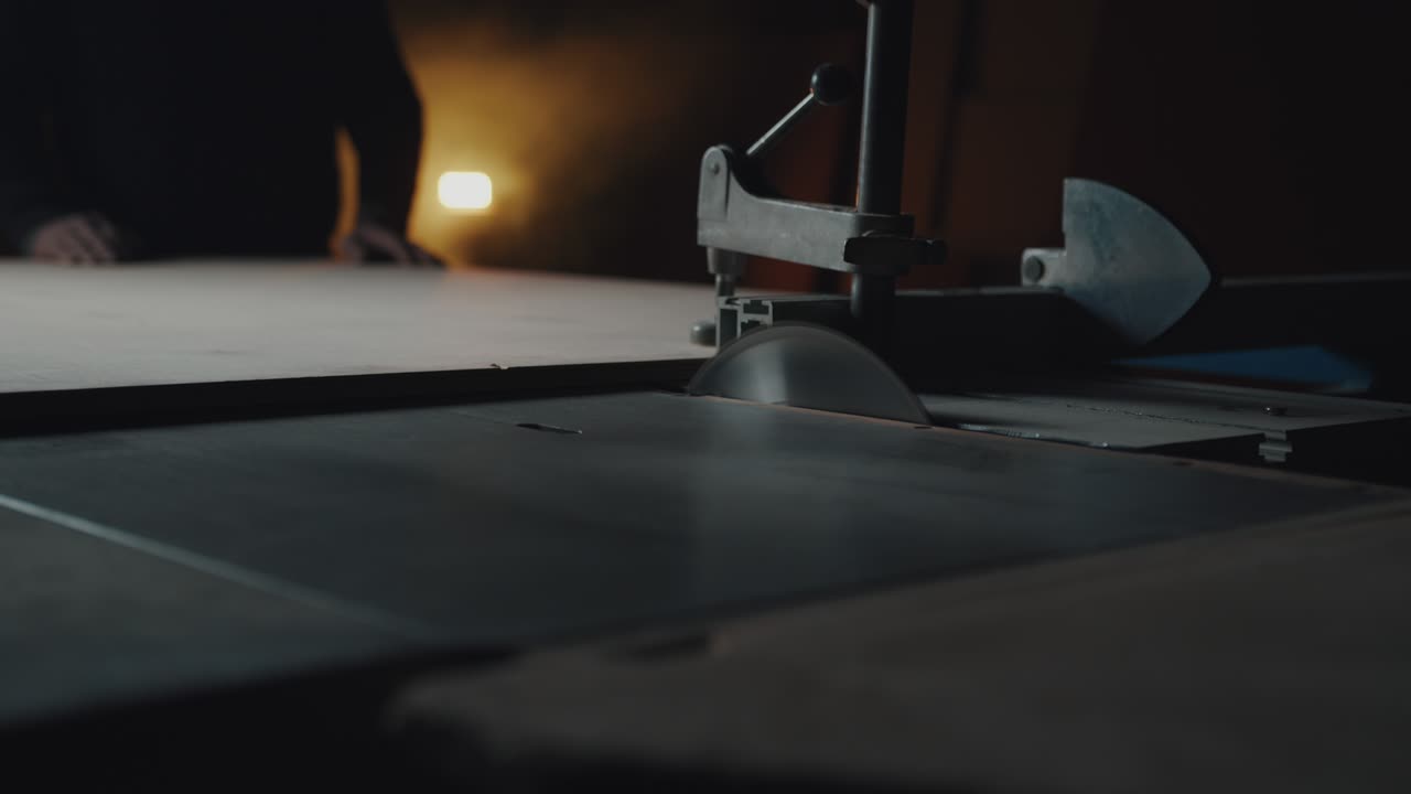 el torno corta una placa de madera. un artesano irreconocible trabaja en su taller. llave oscura, imagen cinematográfica