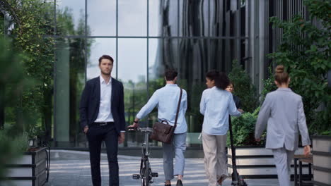 Two-employees-walking-holding-electric-scooter-rental-bicycle.-Downtown-morning