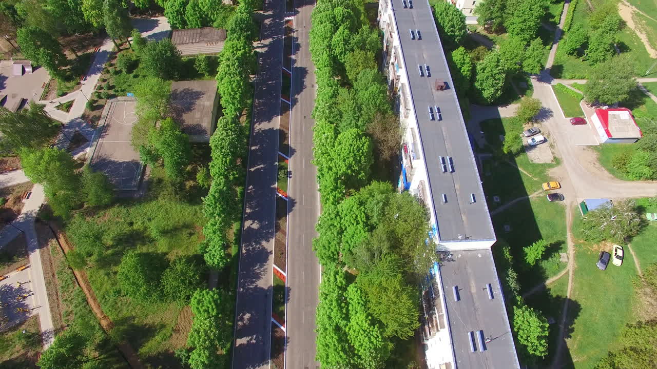 Two-ways road passing through the city. Drone flying along the way to the outlook of a beautiful sunny city at the backdrop of nature.