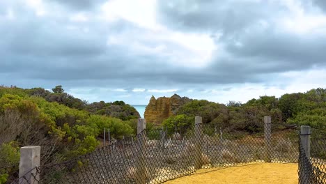 a serene coastal pathway with lush vegetation and distant cliffs under a cloudy sky, captured on great ocean road