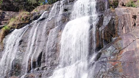 Camera-panning-over-a-cascading-waterfall-falling-from-a-steep-mountain