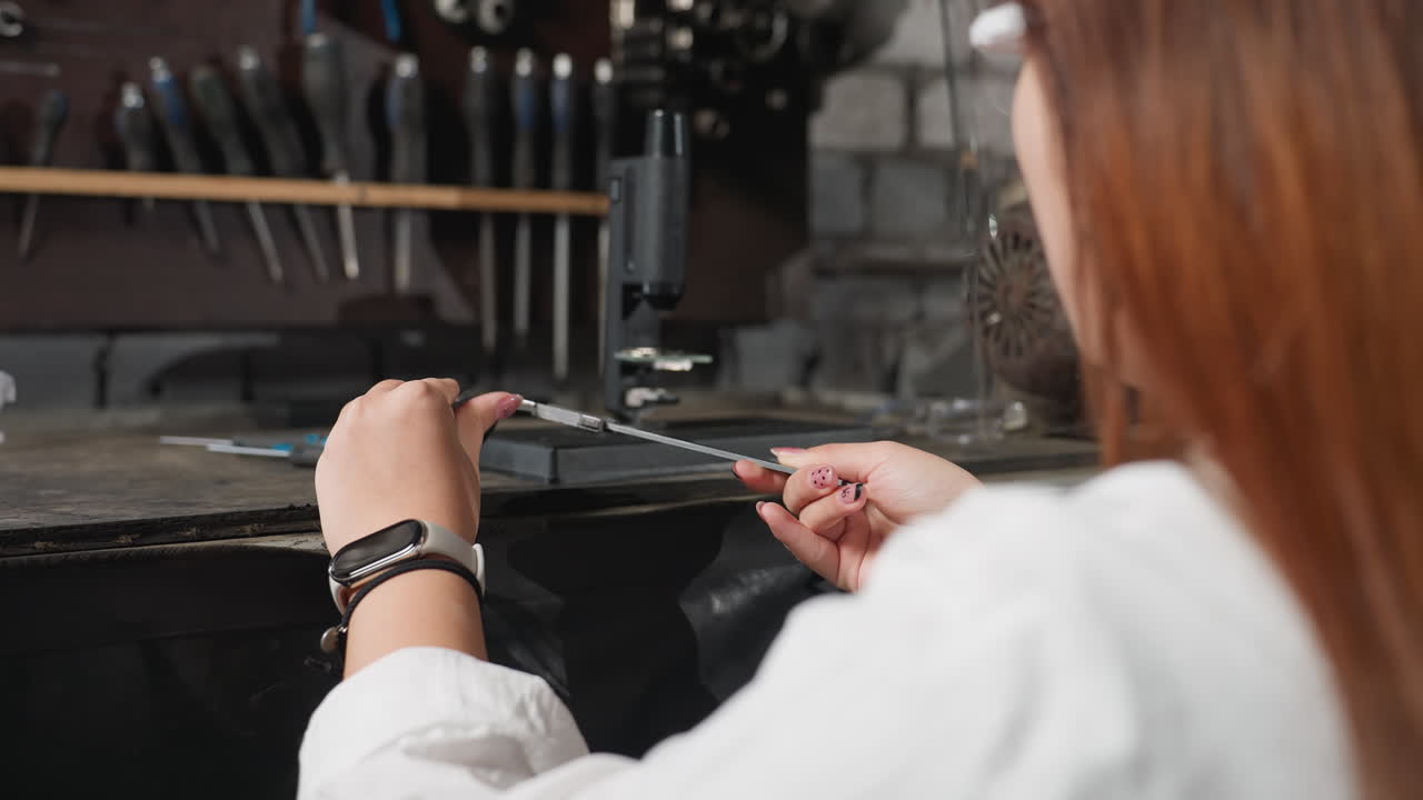 крупный план женщины с защитным щитом для лица, рассматривающей механический инструмент, окруженный различными другими механическими инструментами в автомобильной мастерской, подчеркивая детально ориентированную работу в инженерии