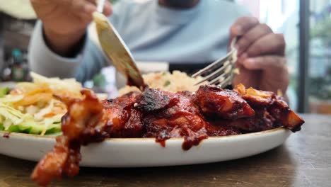 person eating bbq chicken with rice and salad