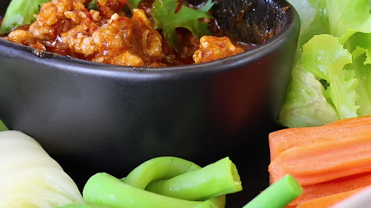 A vibrant display of fresh vegetables surrounding a bowl of spicy dip, perfect for healthy snacking.