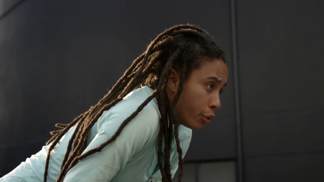 vista lateral de una joven mujer afroamericana descansando después de hacer ejercicio en la ciudad 4k