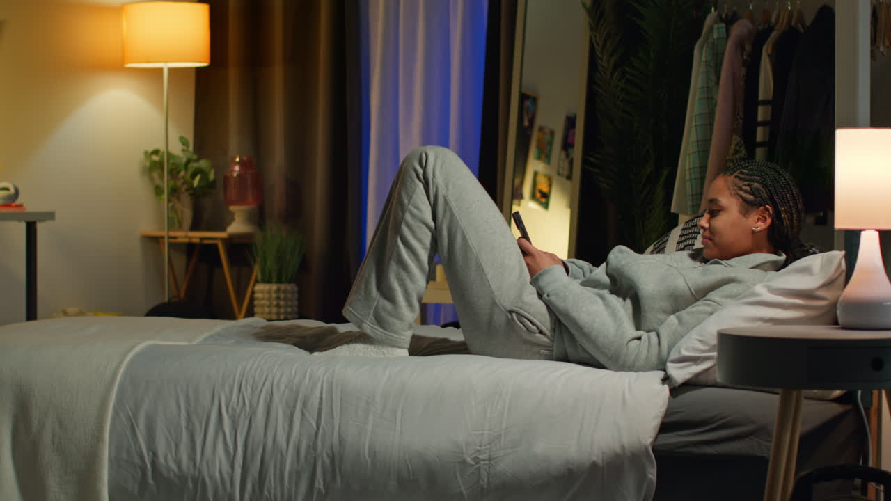 Teenage Girl Using Smartphone in Bedroom at Night