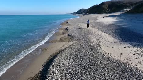 a young man walking on a gravel beach