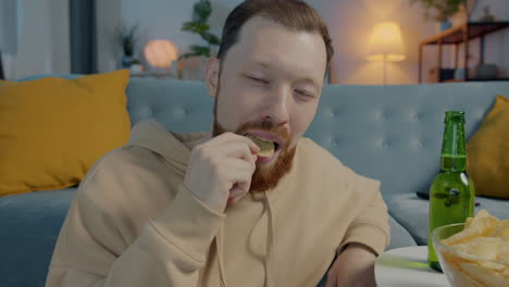 man relaxing at home with beer and chips
