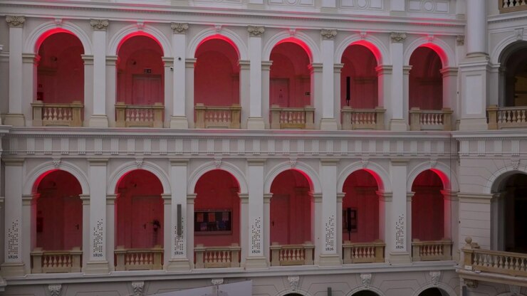 Luzes vermelhas brilham dentro de fileiras de janelas em arco na Universidade de Tecnologia de Varsóvia, Polônia. Tomada estática