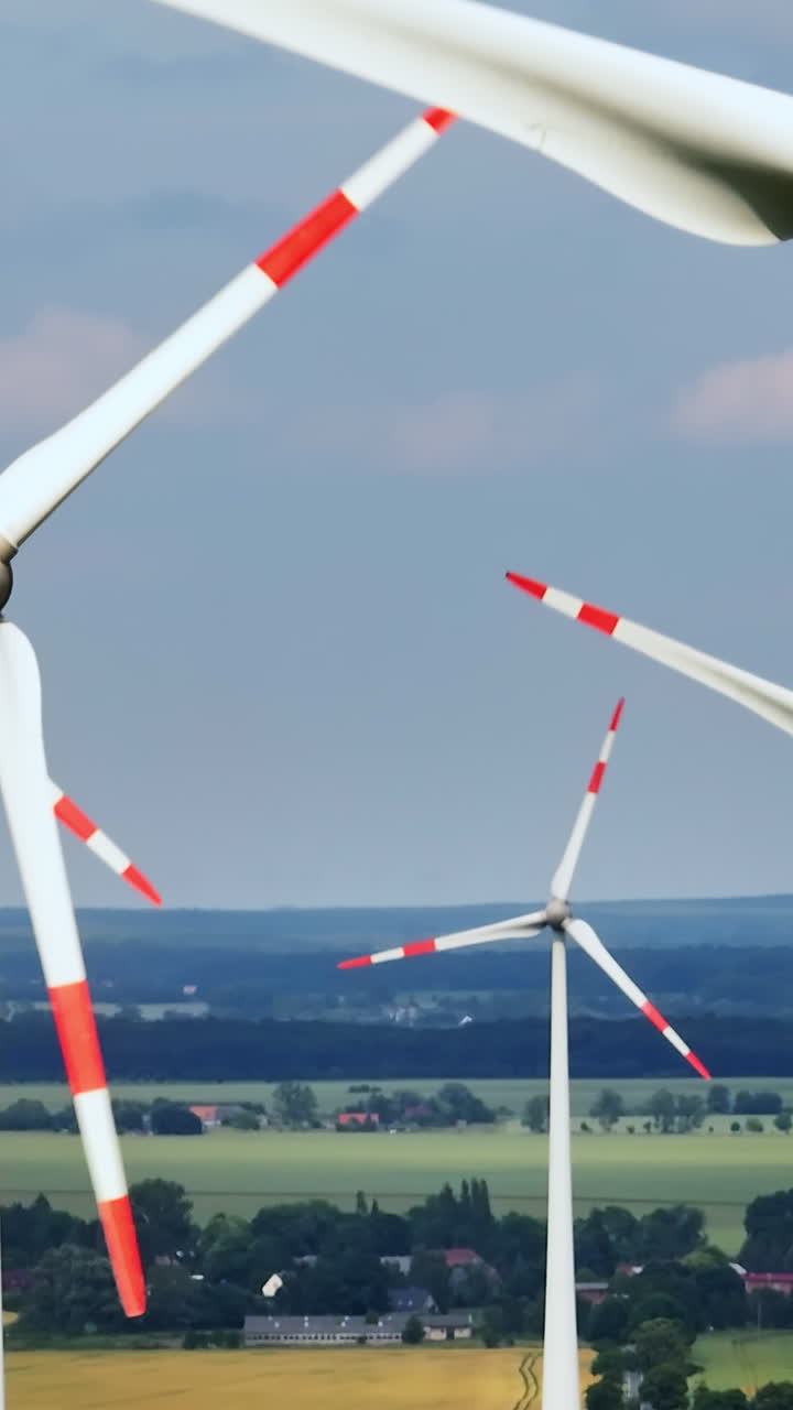 Vertical aerial of rotating wind turbines generating energy, sunny, summer day