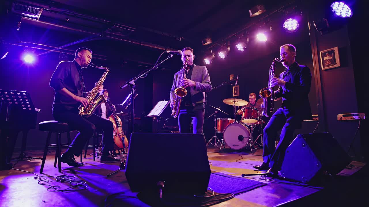 Una band jazz si esibisce sul palco in un club scarsamente illuminato. Il video grandangolare riprende i musicisti che suonano.