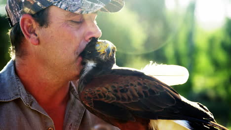 man kissing falcon on a sunny day