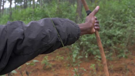 una toma de cámara lenta de un hombre africano disparando una caza tradicional y un arco y una flecha