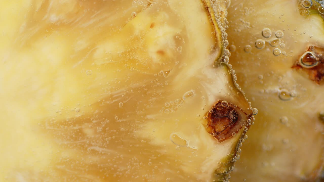 신선한 파인애플 조각은 공기 거품으로 물에 잠겨 있습니다.