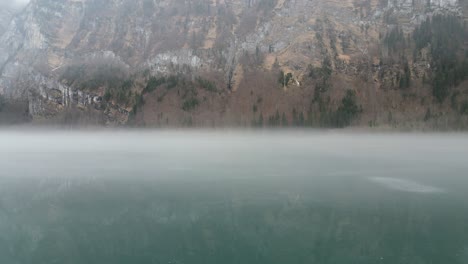 Klöntalersee-Glarus-Suiza-Volar-A-Través-De-La-Niebla-Sobre-El-Lago-Suave-Espejo