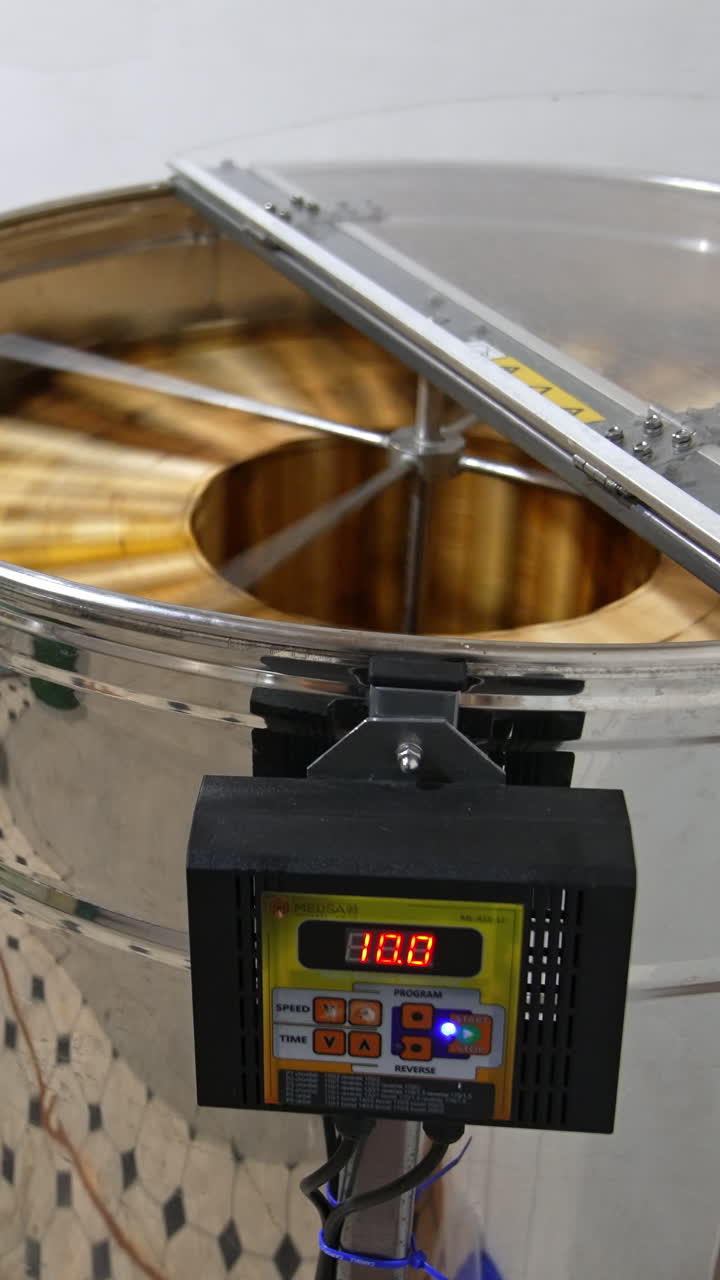 Electric machine with metal carcass working indoors. Honey frames rotating in the apparatus to extract organic product. Vertical video
