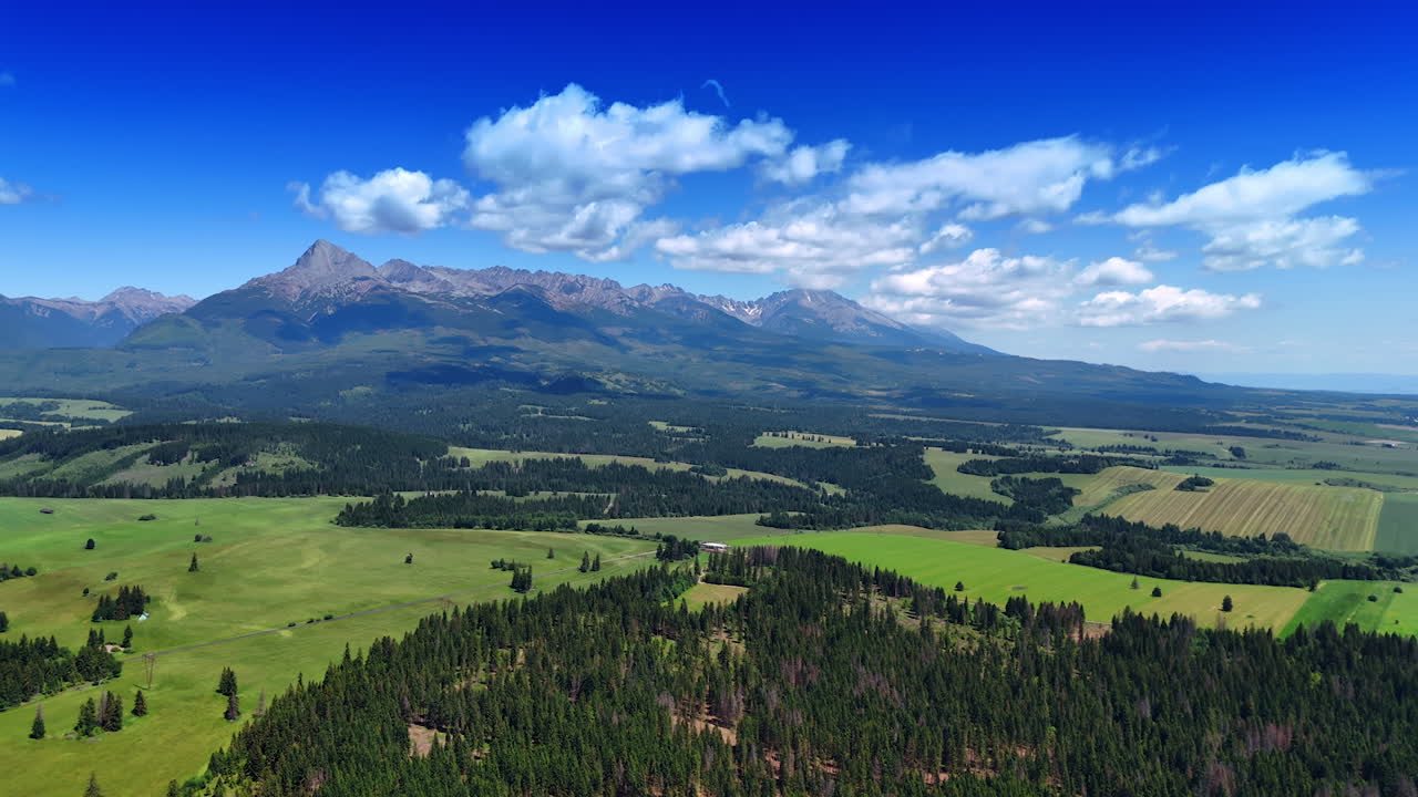 Breath-taking scenery of the beautiful wilderness on sunny summer day. White fluffy clouds hang in the blue sky over the Tatras