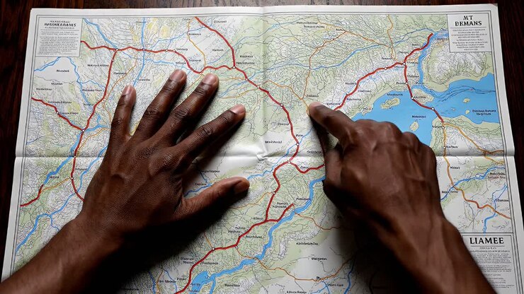 Mains explorant une destination sur une carte de voyage en papier.