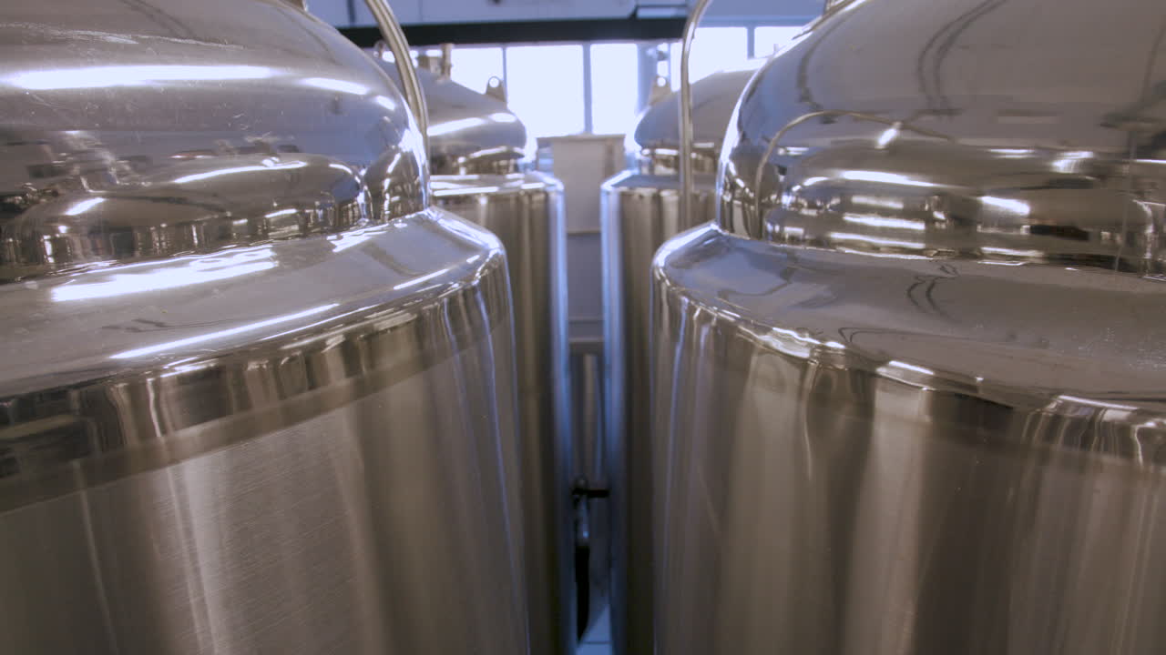 Slow tilt down between rows of stainless steel fermentation tanks in a brewery