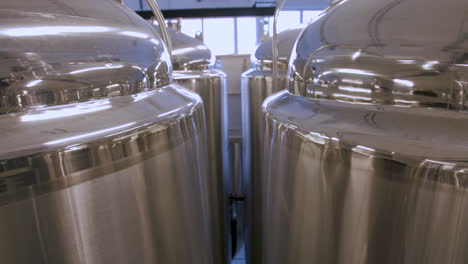 slow tilt down between rows of stainless steel fermentation tanks in a brewery