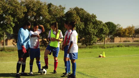 equipo de fútbol femenino discutiendo tácticas en el campo de fútbol.
