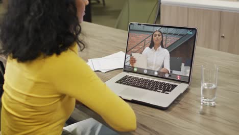 Biracial-businesswoman-using-laptop-for-video-call-with-biracial-business-colleague