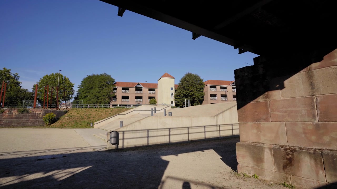 Vista sotto il ponte al Ravelin V con strutture storiche in pietra e lo spazio pubblico circostante in una giornata di sole a Saarlouis, Germania.