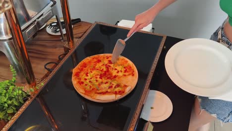 woman serving herself pizza at a buffet