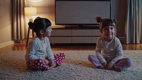 two girls in pajamas talking in the living room