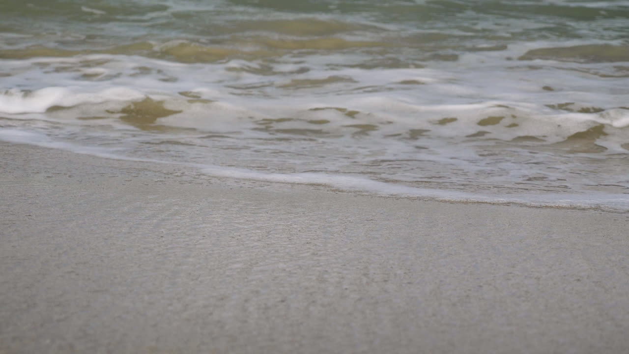 아름다운 초록색 파란색 바다는 부드럽게 해안으로 향하고 아름다운 모래 해변에 부 ⁇ 히고 있습니다.